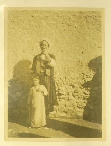 Arab man and boy standing in front of wall.