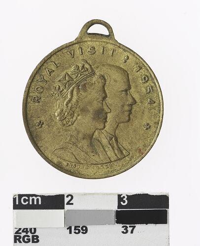 Round gold coloured medal with profile of a man and crowned woman, text surrounding.