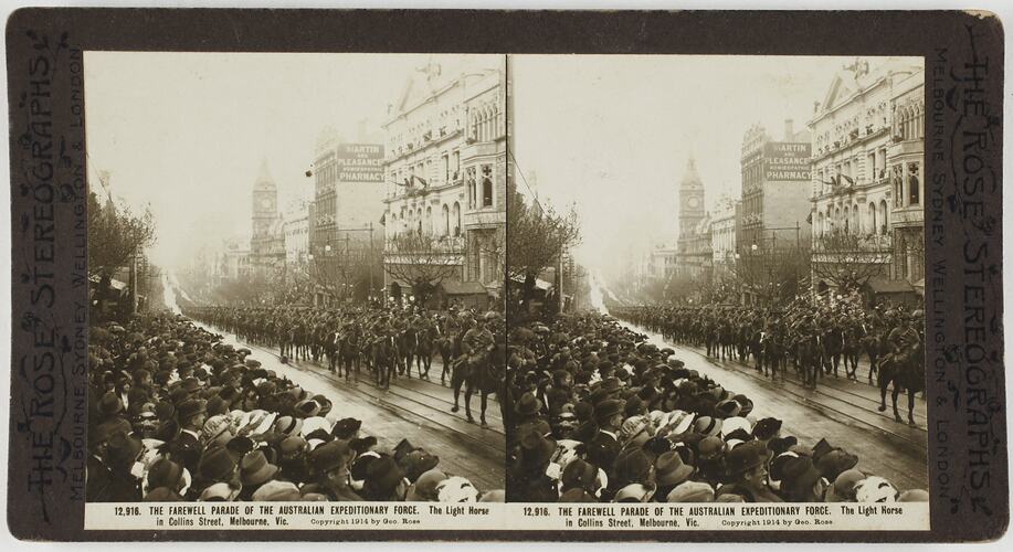 Soldiers marching in formation down city street with crowds of people on left.