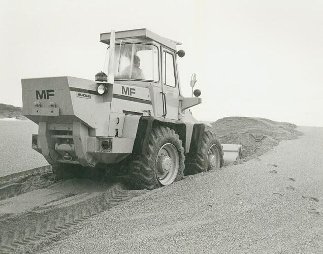 Man operating a front end articulated loader in a sand pit.