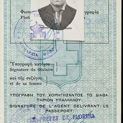 White passport page with blue printed pattern. Blue printed text and handwriting. Photo of male.
