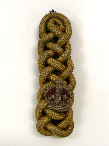 Gold shoulder epaulette of thick woven chord, with gold and red crown fabric patch.