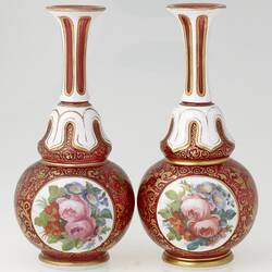 Pair of ruby red and white blown glass vases with gilt arabesque style tendril design, and enamelled floral panels.