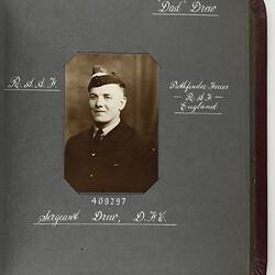 Dark page with handwritten white text and photograph of servicemen in centre.