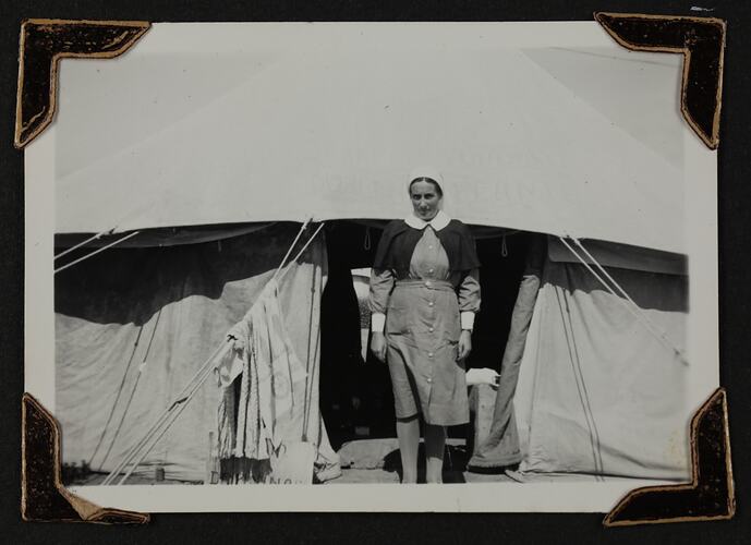 Women wearing a nursing uniform standing outside tent.