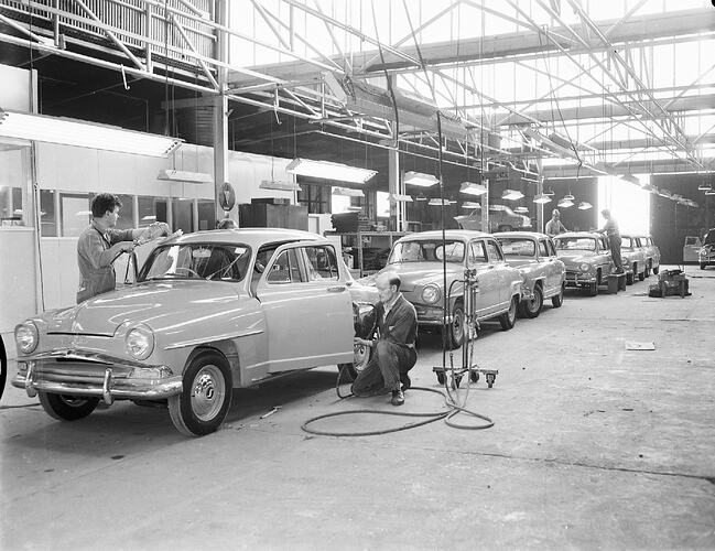 Monochrome photograph of a vehicle manufacturing plant.