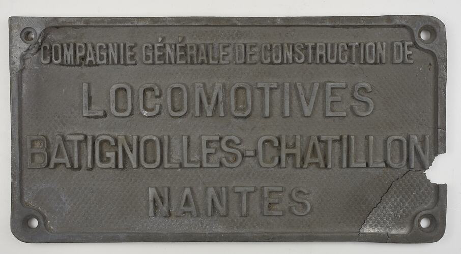 Rectangular metal plate with raised text. Damaged. Lower right corner broken off but in position.