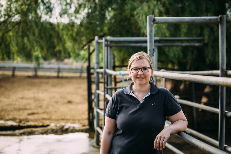 Woman leaning on a metal cow enclosure.