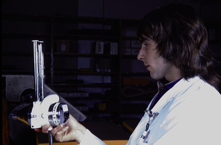 Man in laboratory coat turning a dial.