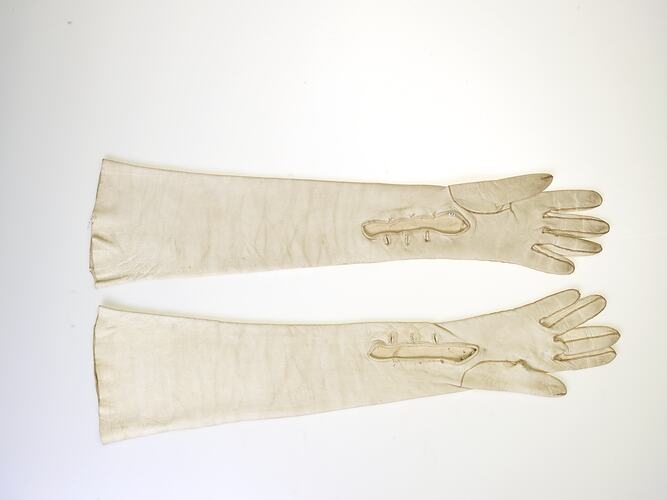 Elbow-length, cream leather gloves with three button holes.