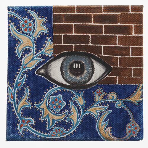Eye painted on red brick wall with blue floral pattern below.