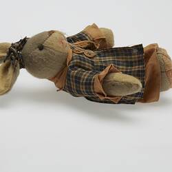 Soft toy rabbit dressed in brown checked dress. Has long whiskers. Laying right profile.
