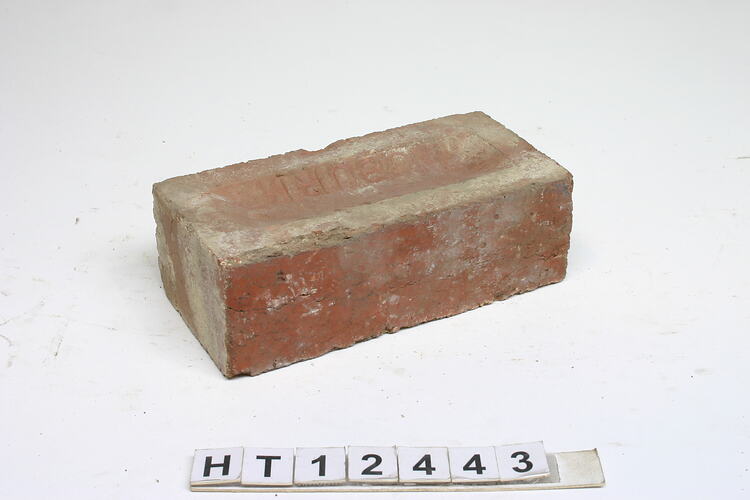 Worn red, machine pressed brick with a frog on one side.