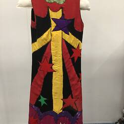 Back of colourful sleeveless coat with stars and shapes. Mostly yellow, red, black and green.