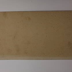 Plain back of a brown exhibition label.