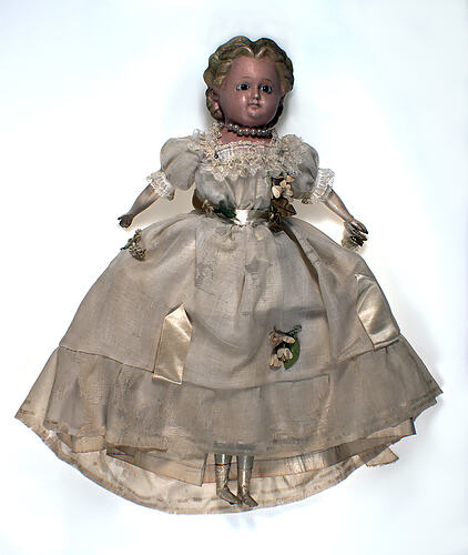 Doll in white dress, face upwards.