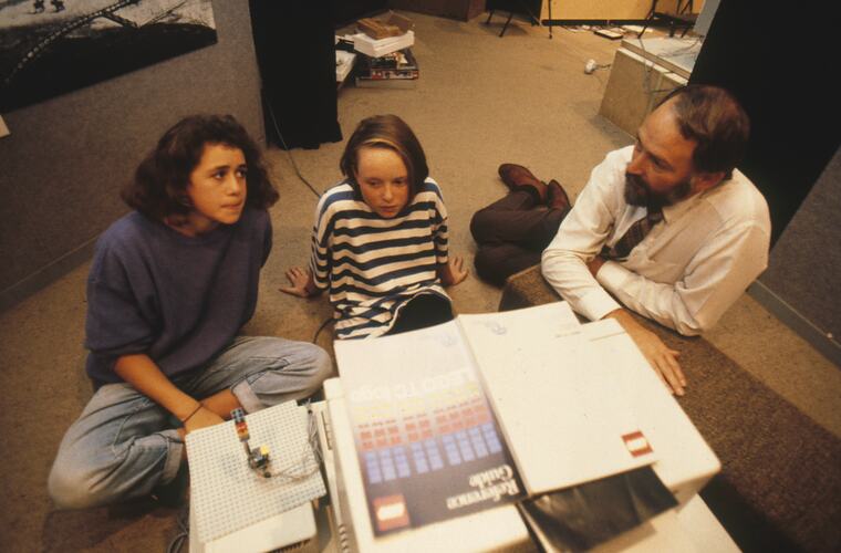 Students and a teacher sitting on the floor studying.