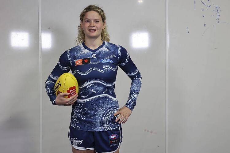 Female Geelong AFLW Footballer wearing blue and white Indigenous patterned guernsey.