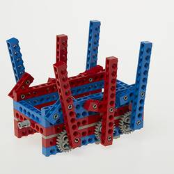 Upside down red, blue and grey LEGO robot with three legs either side.