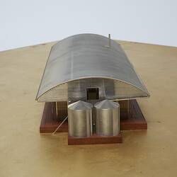 Model of a house with an arched roof, corrugated iron and wide expanses of glass.