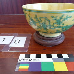 Porcelain bowl with decoration of fruit trees, on a wooden base.