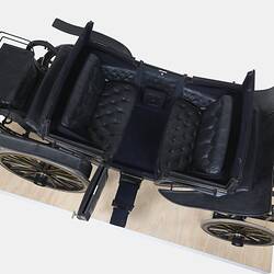 Top view of black coach with four rubber tyres. Yellow and brown lining, and the Australian coat of arms on each door.