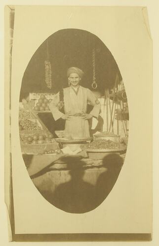 man standing in fruit and vegetable market stall.