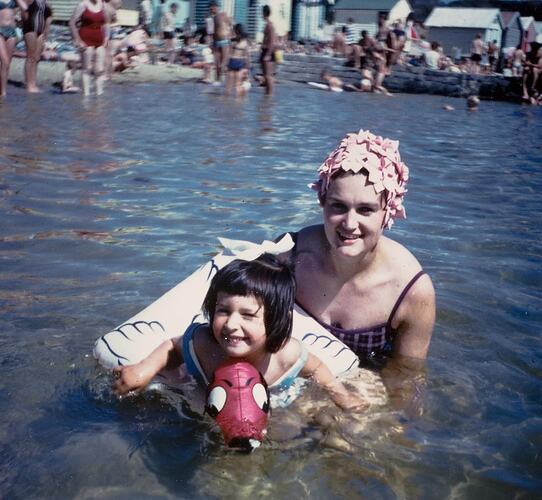 Digital Photograph - Woman in Bathing Cap holding Daughter in Inflatable Water Toy in Sea, circa 1968