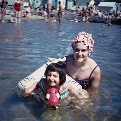Digital Photograph - Woman in Bathing Cap holding Daughter in Inflatable Water Toy in Sea, circa 1968