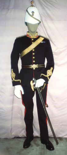 Black military uniform jacket on mannequin, with red collar and gold embroidery waist, front view.