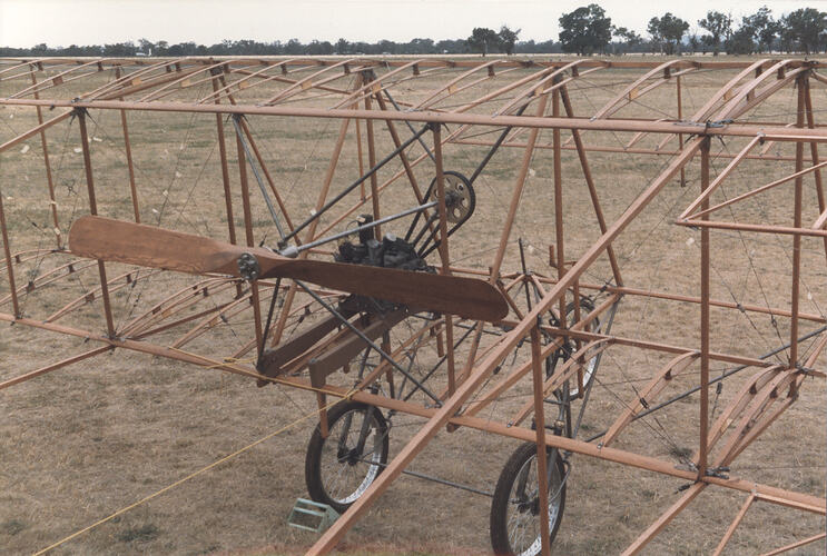 Close-up of airframe of biplane in field.