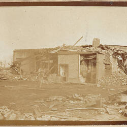 Damaged house surrounded by rubble.