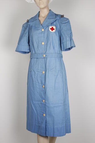 Mid-blue linen dress, buttons, red cross, badges.