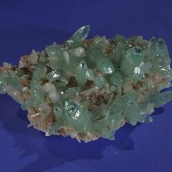 Pale green and white crystals on a grey rock.
