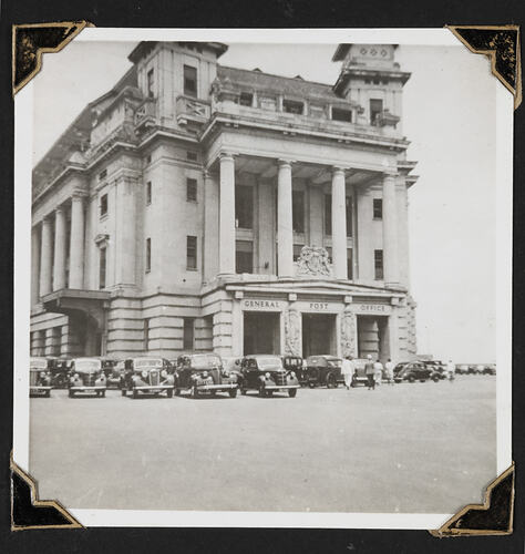 Building with portico and row of cars in front.