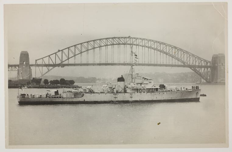 Navy Ship in harbour with bridge behind.