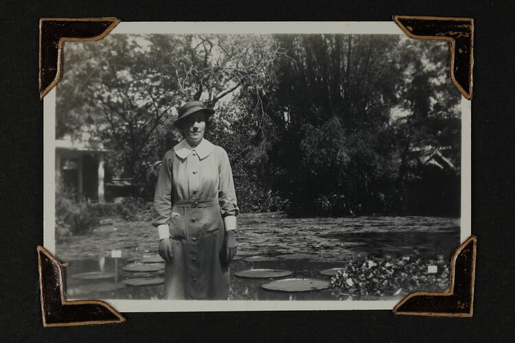 Woman in uniform standing in front a pond with trees behind.