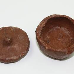 Clay toy pot with lid off, viewed from above.