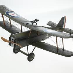 Green model airplane. Circle on top of each wing. Left front three-quarter view.