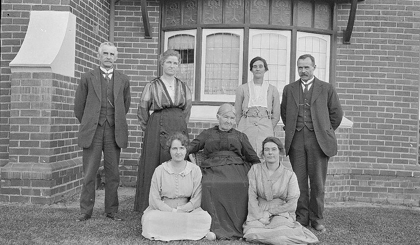 Monochrome negative of a group near a house.