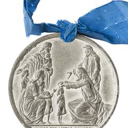 Round silver medal with biblical scene of Jesus and children. Suspended from blue ribbon.