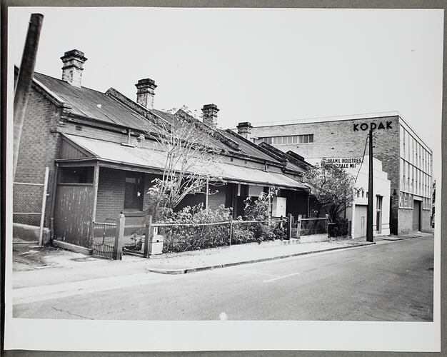 Street view of several terraced houses, white building and brick building with Kodak branding.