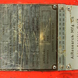 Red cylindrical container with two electrical cords at one end.