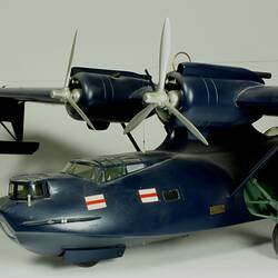 Navy twin propeller aeroplane model with three wheels. Red and white flags affixed near cockpit.