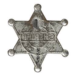 Back of toy star-shaped silver metal sheriff badge.