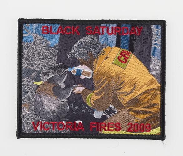 Cloth badge with image of firefighting man in yellow feeding water to a koala.