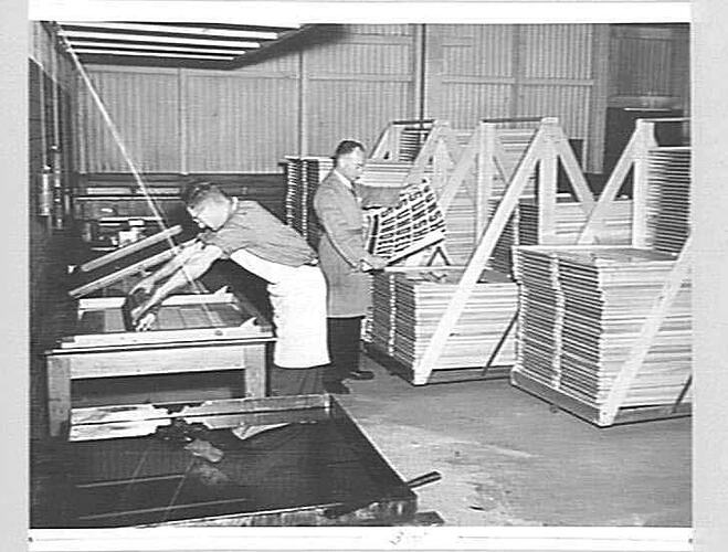 Two men using equipment in printer workshop.