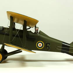Dark green model airplane. Circle pattern on top on each wing. Right profile.