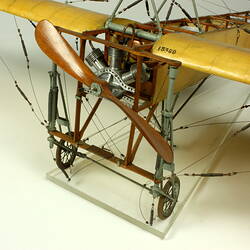 Model aeroplane with exposed wooden frame and off white panelling. Wheels and propeller detail.