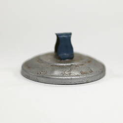 Side view of tiny aluminium pot lid showing handle.